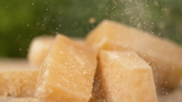 SLOW MOTION, MACRO, DOF: Cool shot of grated parmesan raining onto the cheese cubes. Delicious organic parmesan cheese is sprinkled over the whole squares. Tasty vegetarian appetizer in the making.