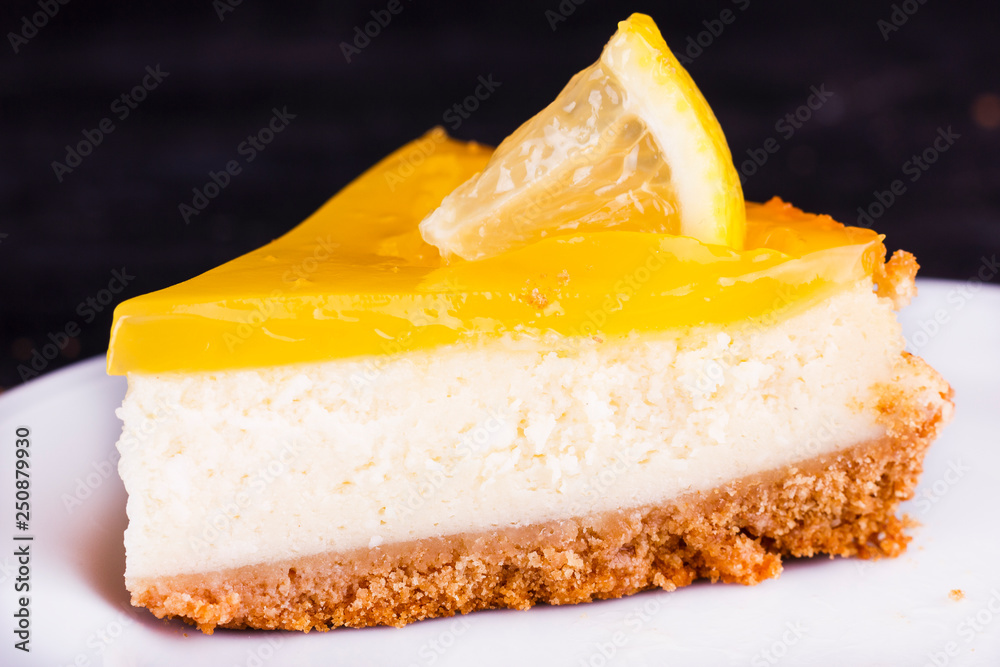 Wall mural lemon cheesecake on black background decorated with lemon zest close up