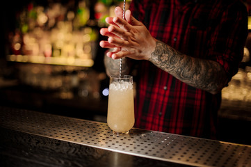 Bartender stirring a Trinidad Swizzle cocktail with the spoon