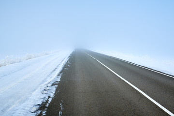Fototapeta premium scenic view of empty road with snow covered landscape while snowing in winter season.