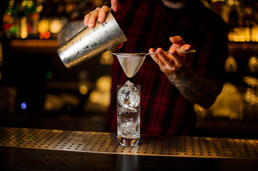 Bartender pouring a Hurricane Punch cocktail from the steel shaker