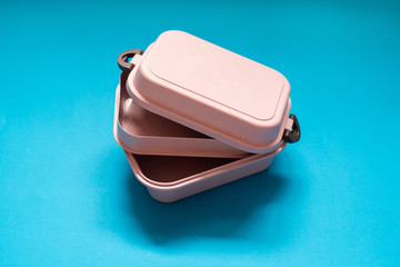 Empty pink bento lunch box on blue background