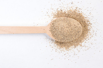 ground white pepper in wooden spoon isolated on white background. top view