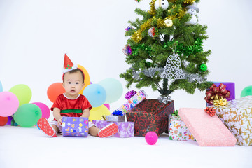 Obraz na płótnie Canvas Baby in a christmas dress playing with presents