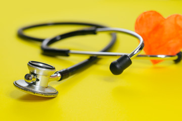 closeup view of stethoscope and red heart on yellow background