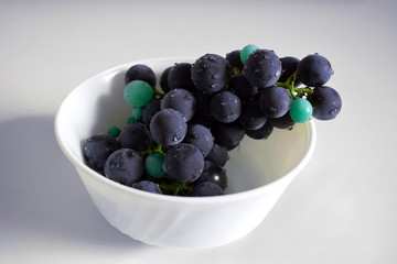 Edited photo of dark violet grapes in a cup with turquoise spheres for grapes that did not develop fully