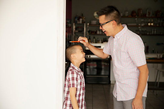 Father measuring son (6-7) in doorway 