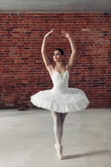 Naklejka premium graceful young talented ballerina standing on toes and looking aside . stamina and hobby concept. full length photo
