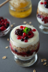 Overnight oats, muesli with berries. Healthy breakfast in glass over grey background. Tasty oatmeals with yogurt.