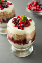 Overnight oats, muesli with berries. Healthy breakfast in glass over grey background. Tasty oatmeals with yogurt.