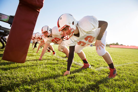 Teenage football players (14-15, 16-17) tackling in school field 