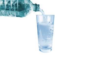 Water is poured from a plastic bottle into a glass, on a white background