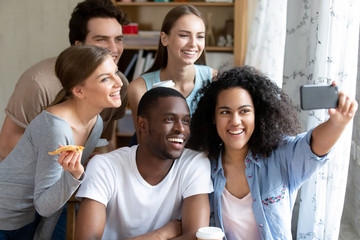 Happy smiling multiracial friends making selfie photo in pizzeria
