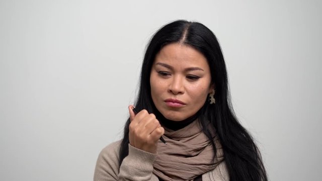 Pretty Asian thinks and clicks the button of a pen