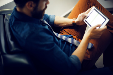 Man sitting in armchair and using digital tablet 