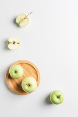 green apples on wooden stand on white background