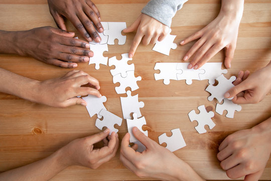 Close up multiracial people, team assembling puzzle, success teamwork