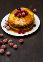 pancakes with jam and berries on wooden black background