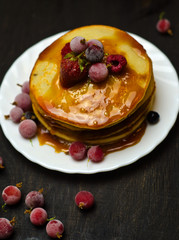 pancakes with jam and berries on wooden black background