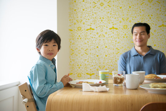 Portrait of boy eating breakfast with father 