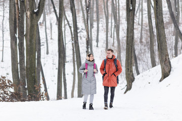 Tourists with backpacks walking at the winter snowy forest and admiring of the landscapes