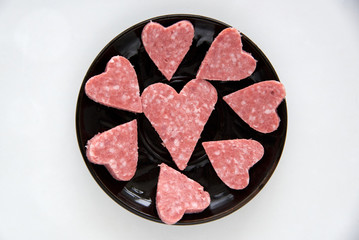 Salami sliced sausage heart-shaped slices on a black plate