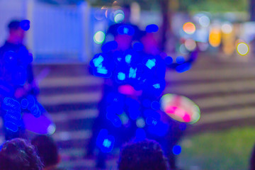 Fototapeta na wymiar Dancers with light glowing costume dancing parade at night during new year festival. Dancers are dancing on stage in robotic costume with led lights illumination. Blurred focus with bokeh background.