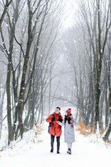 Fototapeta na wymiar Tourists with backpacks walking at the winter snowy forest and admiring of the landscapes