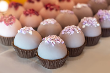 Tray of small lavender cupcakes decorated with culinary mastic and white and pink toppings