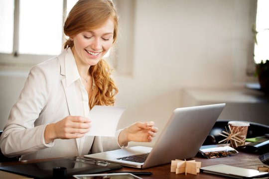 Smiling young business woman looking at picture 