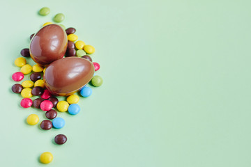 Chocolate Easter eggs and sweets on pastel green background
