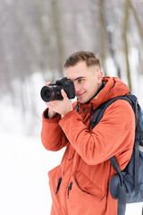Fototapeta na wymiar Blonde photograph boy shooting winter landscapes while walking in the forest