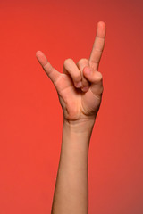 Close-up of a man's hand with a goat's sign isolated on a red background