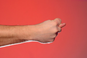 Man's hand with a fig's sign close-up is isolated on a red background