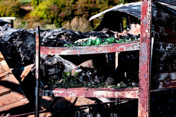 Naklejka premium Damaged supermarket after arson fire with burn debris of twisted metallic structure after intense burning with gate protection