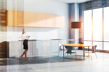 Woman in concrete kitchen corner with table