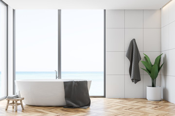 White tile bathroom interior, tub and towel