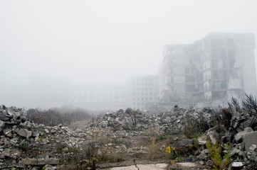 The remains of concrete fragments of gray stones on the background of the destroyed building in a foggy haze. Copy space