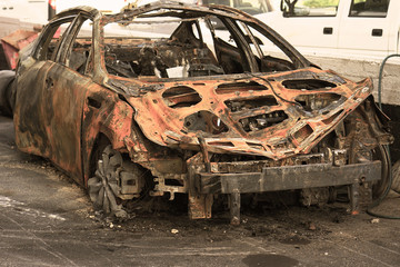 Burned car, burned-out car body. Road wreck accident or arson fire burnt wheel car vehicle junk. Toning.