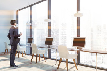 Man in panoramic office corner with white chairs