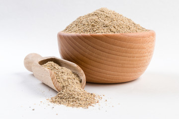 ground white pepper in wooden bowl and scoop isolated on white background