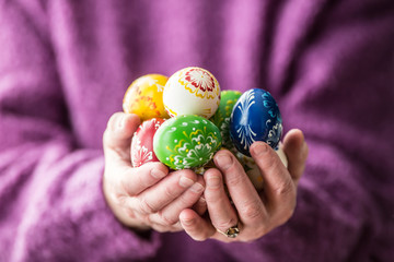 Close-up multicolored easter eggs in the senior woman hands