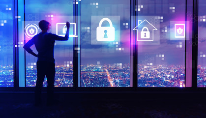 Cyber security with man writing on large windows high above a sprawling city at night