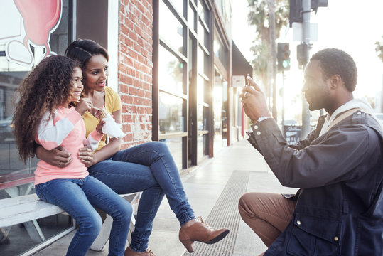 Man photographing his family on sidewalk 