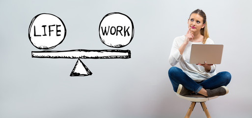 Life and work balance with young woman using her laptop on a grey background