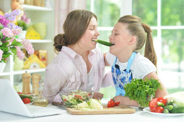 Two girls having fun while preparing fresh salad