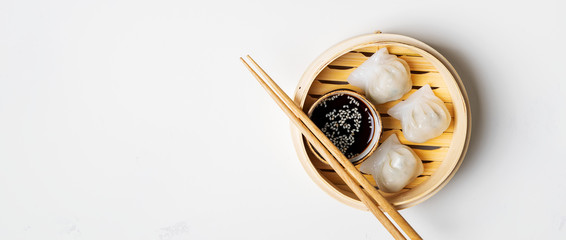 Traditional chinese steamed dumplings Dim Sums in bamboo steamer with sauces and chopsticks on...