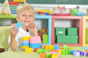 Portrait of cute boy playing with colorful plastic blocks
