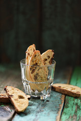 Traditional Europe sweet pastry biscotti or cantucci with raisins in glass on old green wooden boards