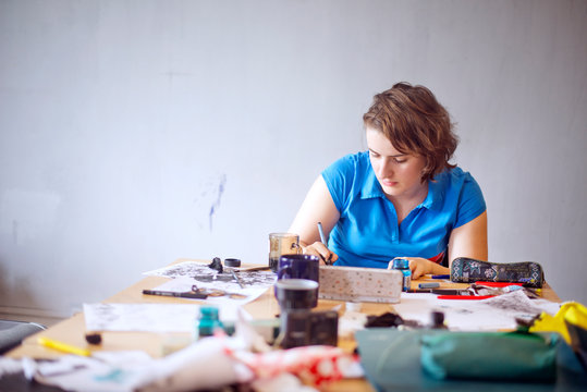 Young woman drawing with art supplies 